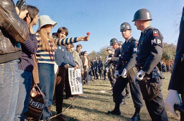Una manifestante ofrece una flor a un policía militar de guardia en el Pentágono durante una manifestación en contra de la guerra de Vietnam. Arlington, Virginia, EEUU. 21 October 1967Fuente: National Archives Record Group 111. Series: Color Photographs of Signal Corps Activity, 1944 - 1981. (111-CC-46331) VENDOR # 139.ARC# 594360. La guerra de Vietnam fue una de las causas principales del fin del dominio económico de los EEUU y una de las causas (por sus elevados gastos militares) del fin de los acuerdos de Bretton Woods.